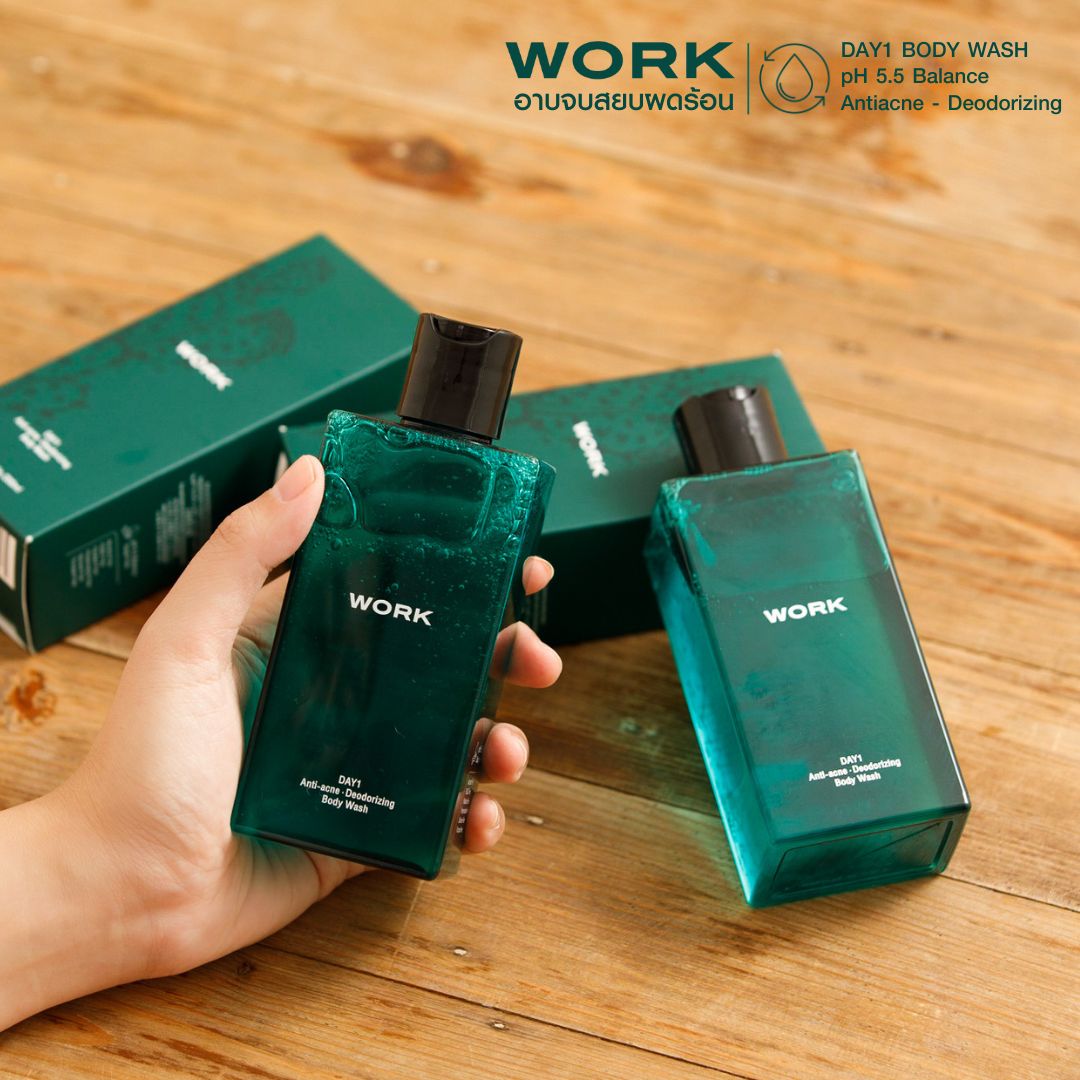 มือถือขวดเจลอาบน้ำ WORK DAY1 Body Wash บนโต๊ะไม้ พร้อมกล่องสีเขียว